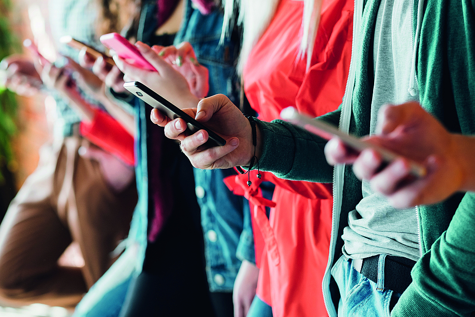 Mediensucht Handy Mehrere Personen halten ein Handy in ihrer Hand