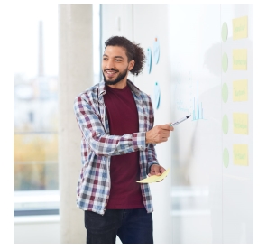 Ein Mann erklärt etwas und bezieht sich auf ein beschriftetes Whiteboard. 